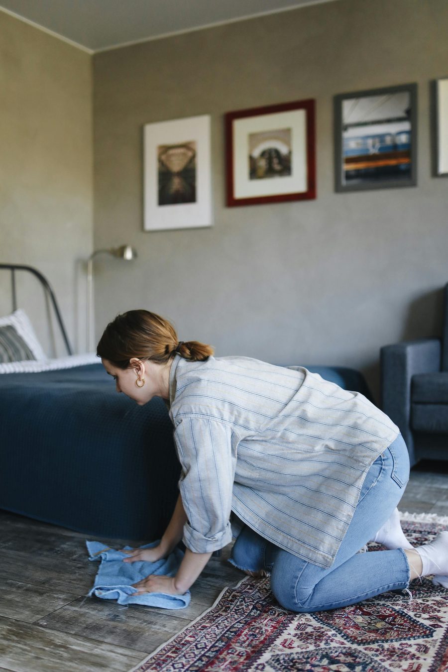 Persona limpiando una superficie del dormitorio con un paño, como referencia del trabajo puntual sin empapar